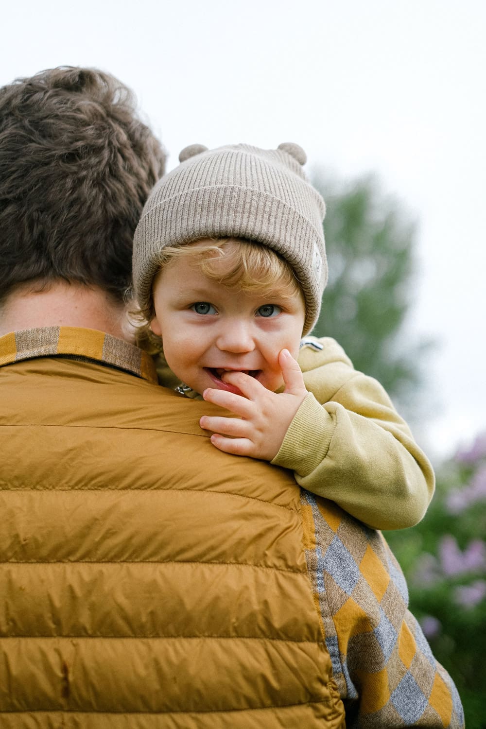child looking at camera while being help by a man