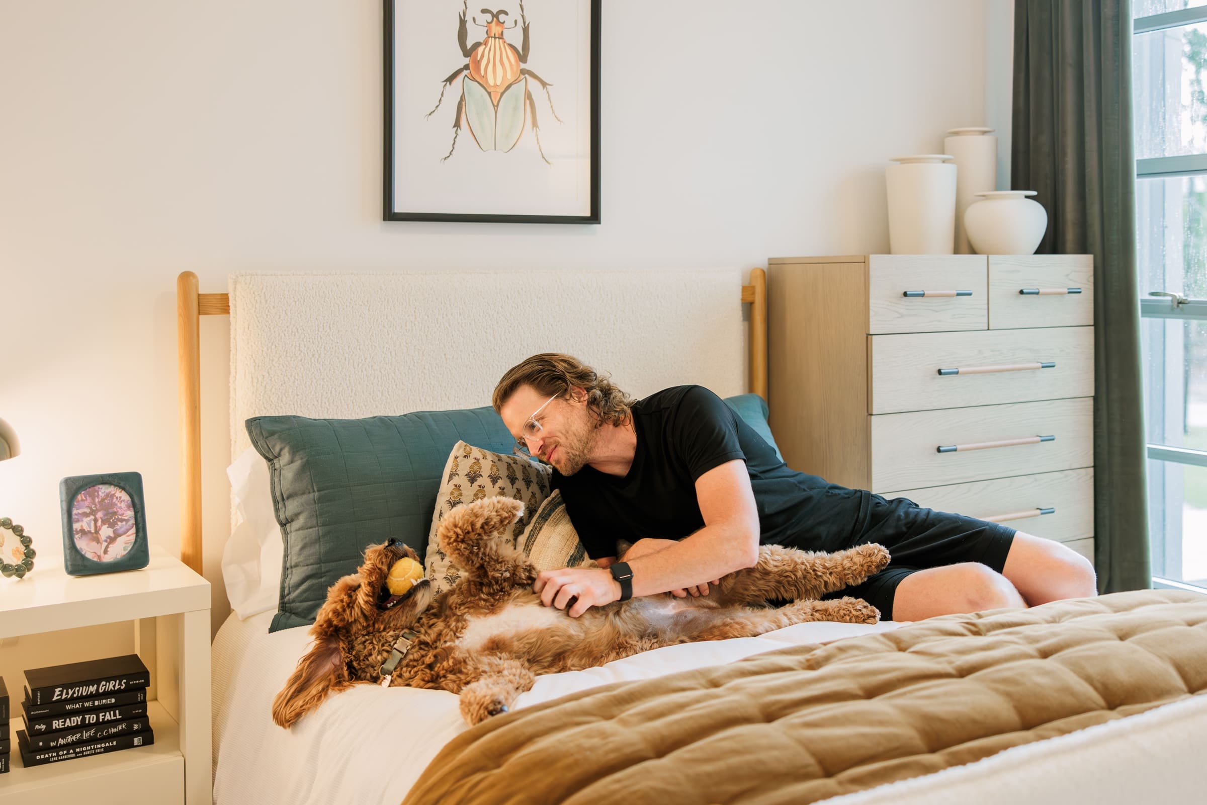 man and dog playing with ball on the bed